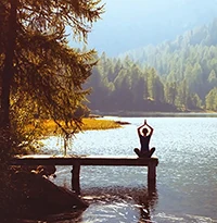 Frau beim Yoga auf einem Steg am Bergsee